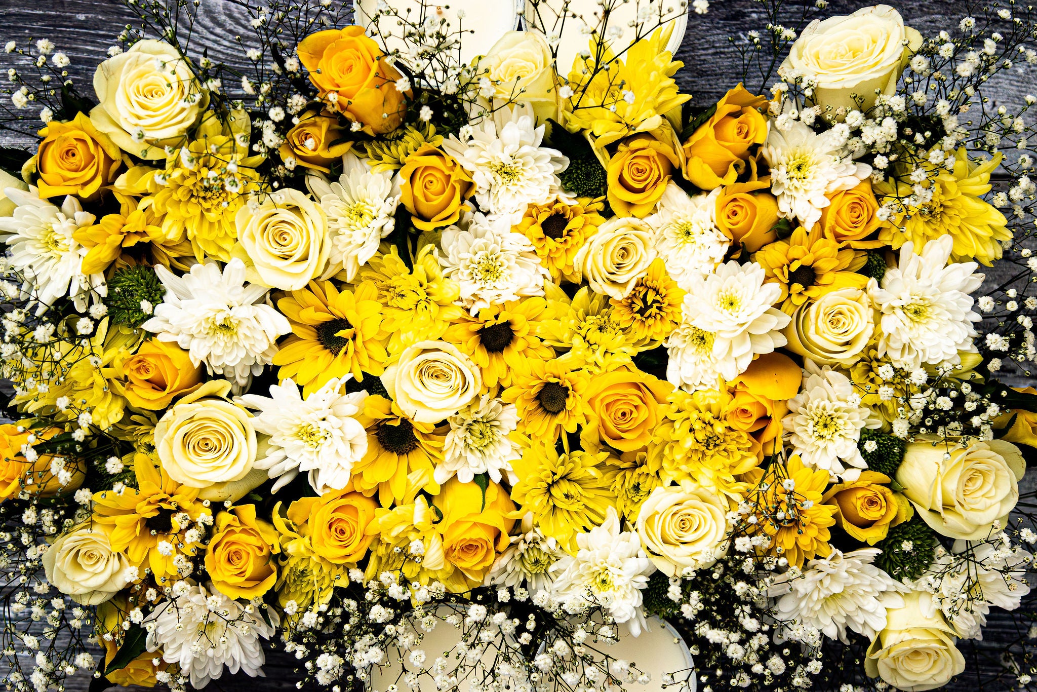 Arrangement of yellow and white flowers on a dark background