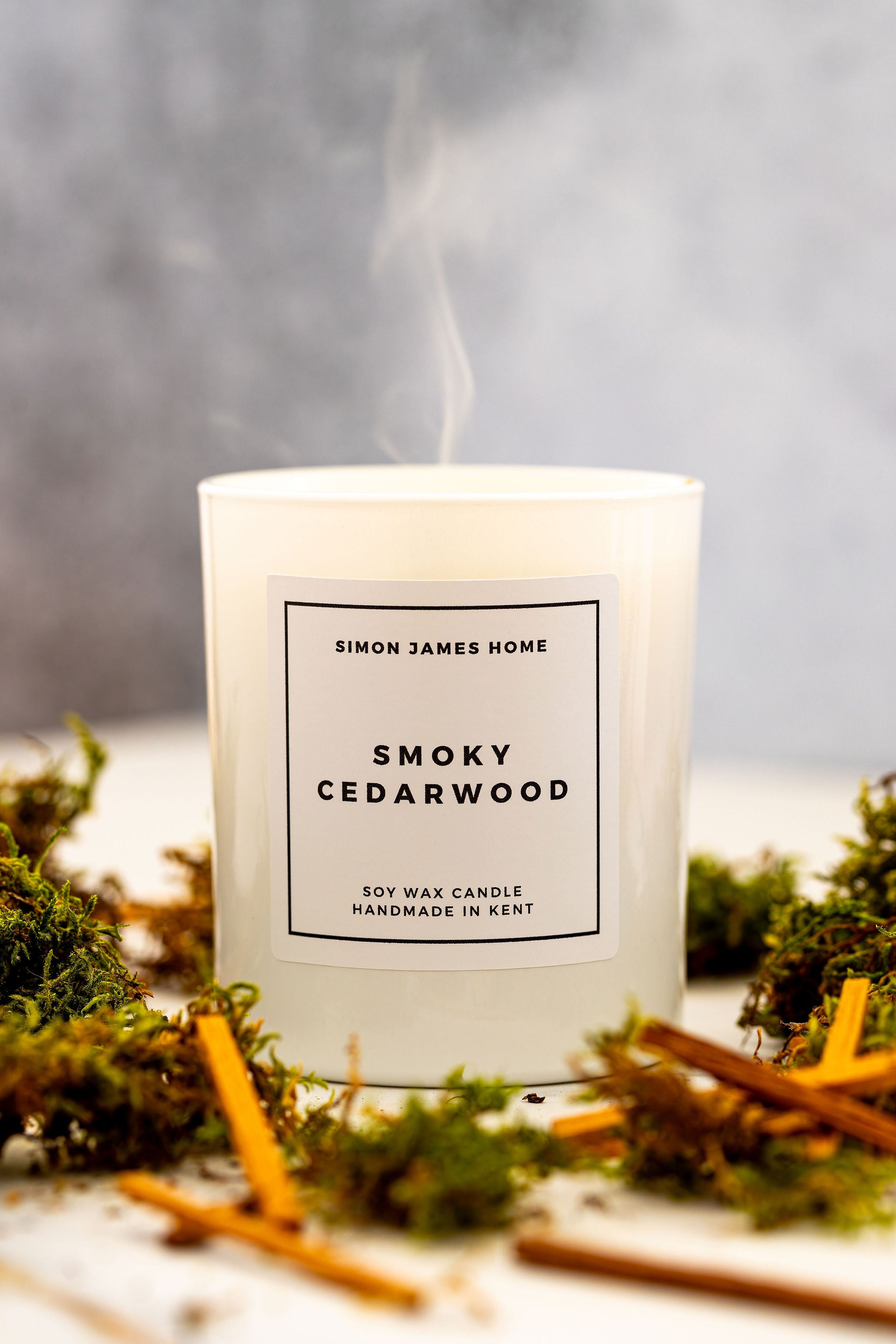 Candle labeled 'Smoky Cedarwood' by Simon James Home with a smoky background.