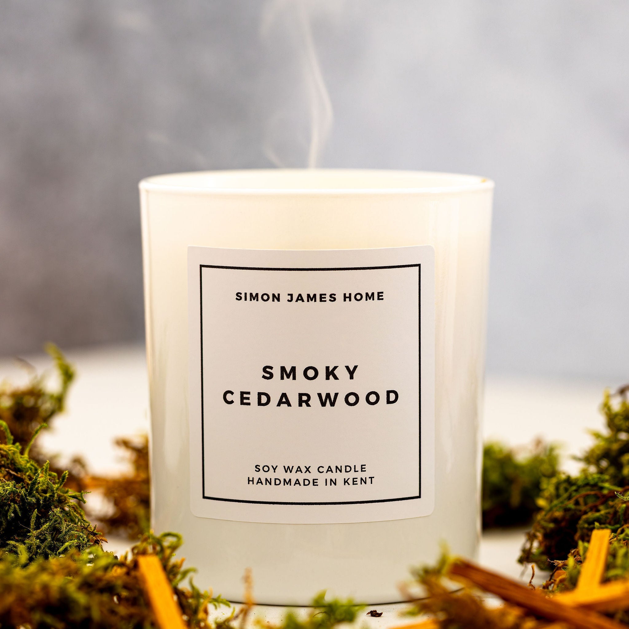 Candle labeled 'Smoky Cedarwood' by Simon James Home with a smoky background.