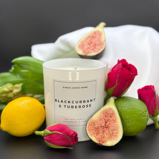 Blackcurrant & Tuberose Candle in white glass container, surrounded by ingredients