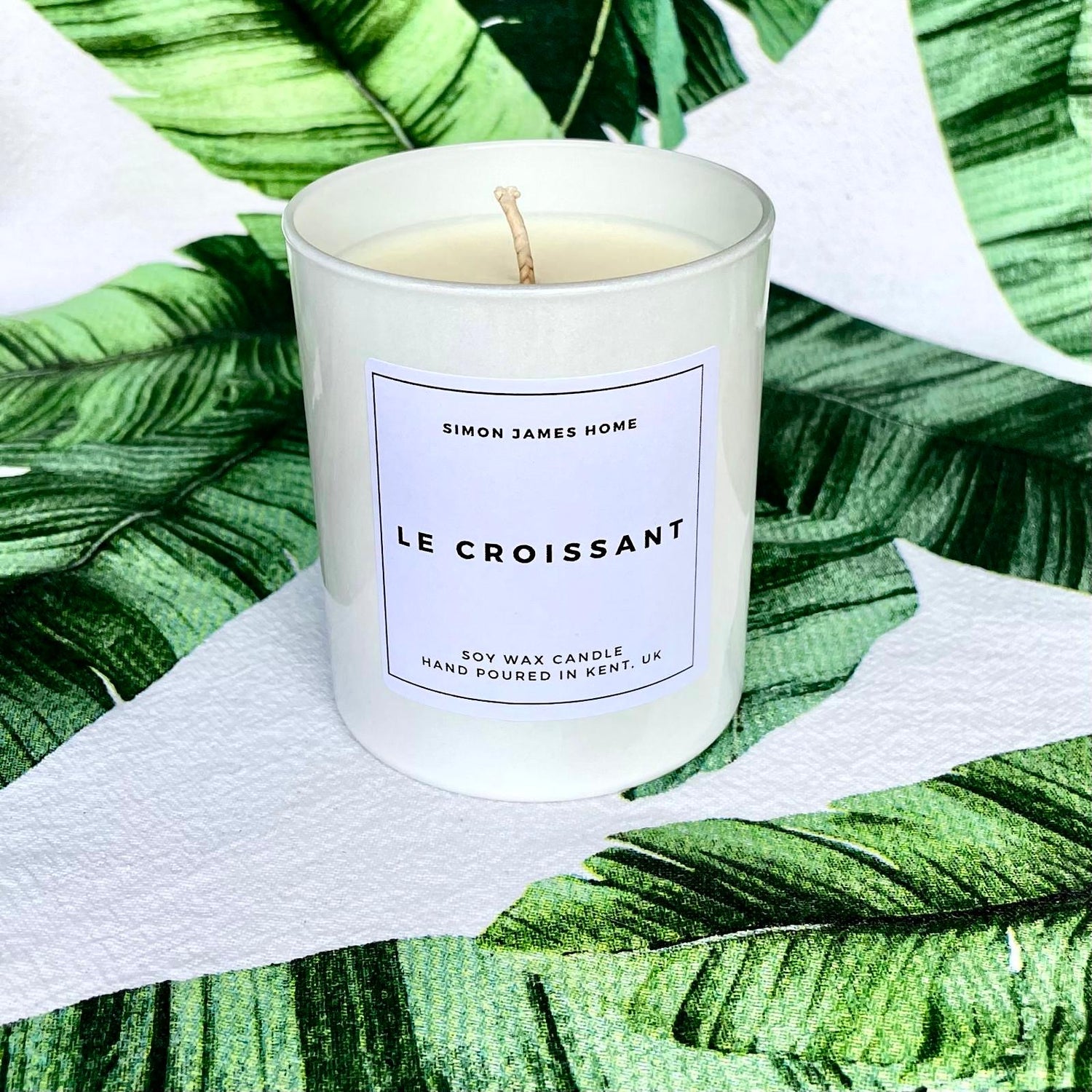 Croissant scented container candle on a green leaf background