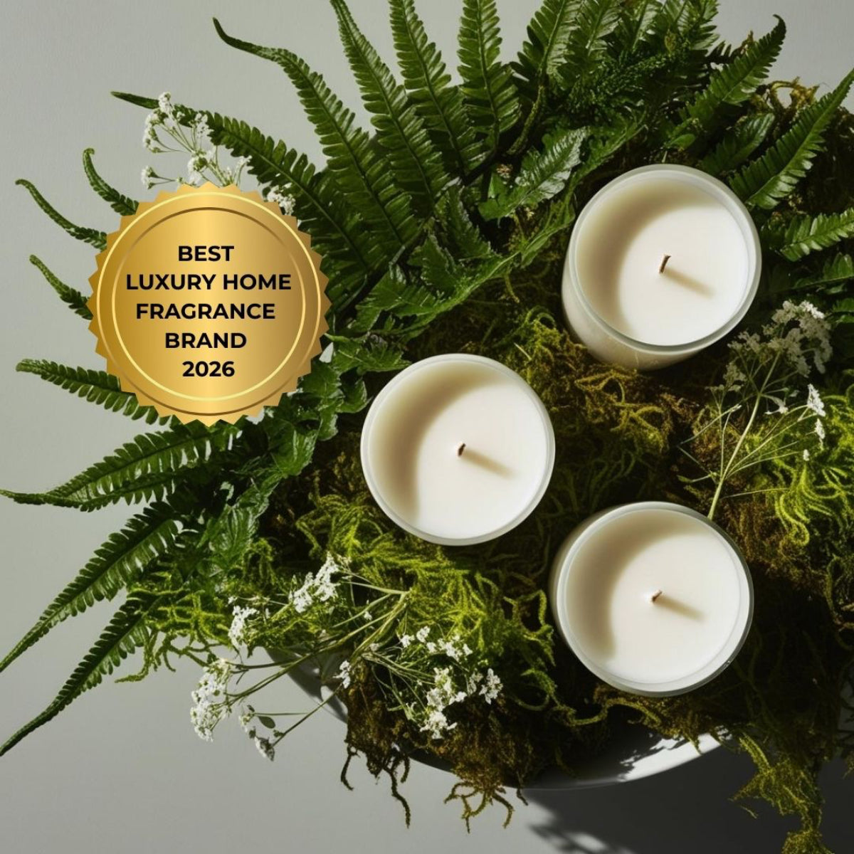 Candles nestled in most and ferns with Best Luxury Home Fragrance Brand 2026 stamp